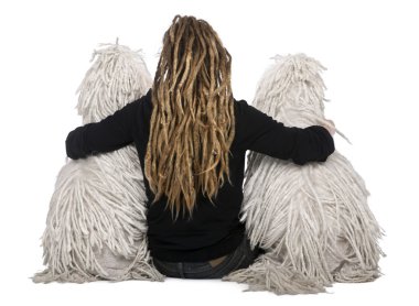 Rear view of two White Corded standard Poodles and a girl with dreadlocks sitting in front of white background clipart