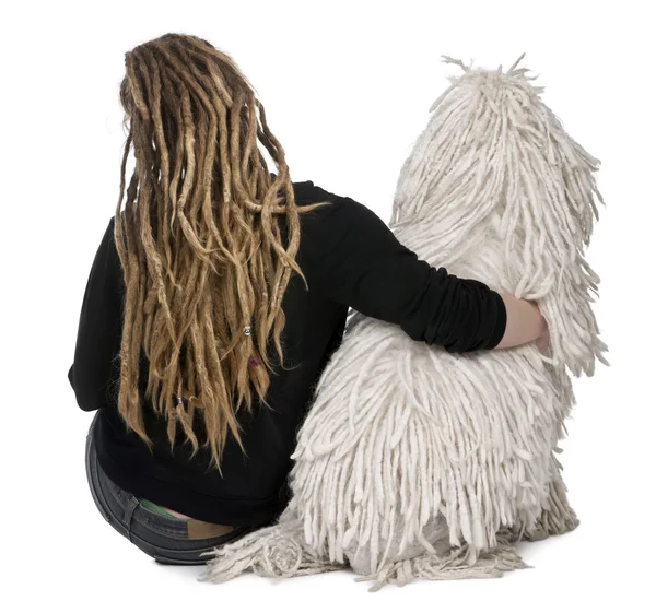 Πίσω όψη της ένα λευκό σχοινόδετο τυποποιημένο poodle και ένα κορίτσι με dreadlocks κάθεται μπροστά από το λευκό φόντο — Φωτογραφία Αρχείου