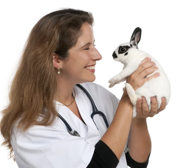 Vet looking at a Dalmatian rabbit in front of white background — 스톡 사진