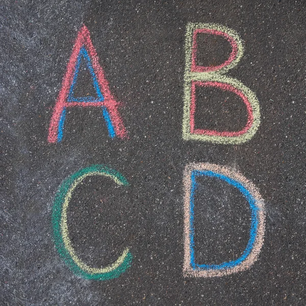 Alphabet letters drawn on asphalt with chalk, a, b, c, d — Stock Photo, Image