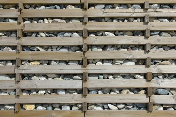 Каменная стена, удерживаемая деревянными досками — стоковое фото