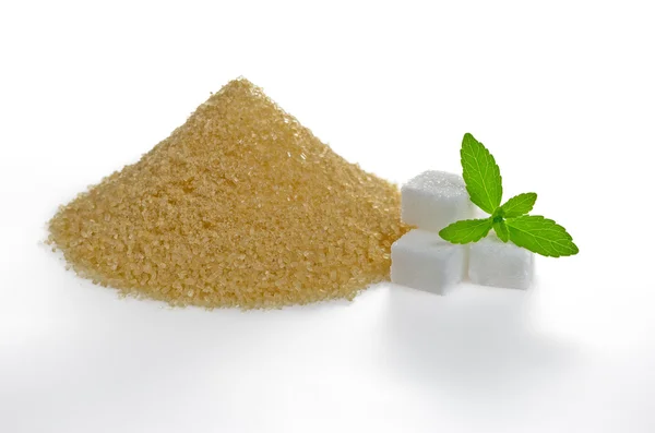 Stevia leaves with sugar cubes and a brown sugar heap — Stock Photo, Image