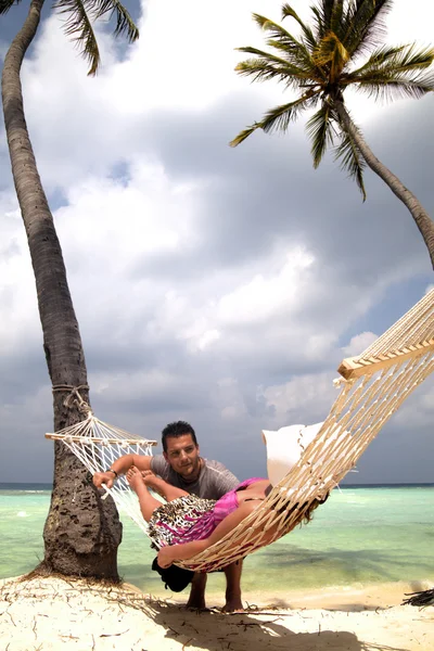 Handsome man chatting to woman in hammock — Stock Photo, Image