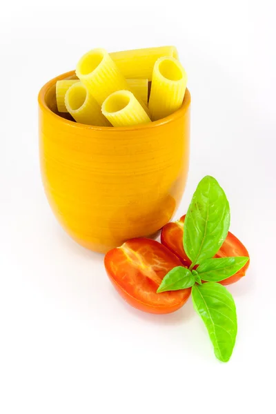 Rigatoni pasta in an orange jar with tomatoes and basil — Stock Photo, Image