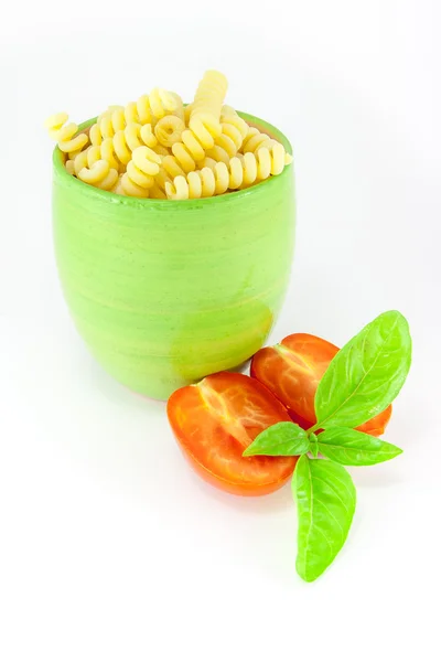 Fusilli pasta in a green jar with tomatoes and basil — Stock Photo, Image