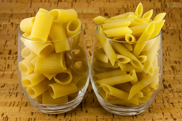 Two varieties of pasta inside two transparent glasses — Stock Photo, Image