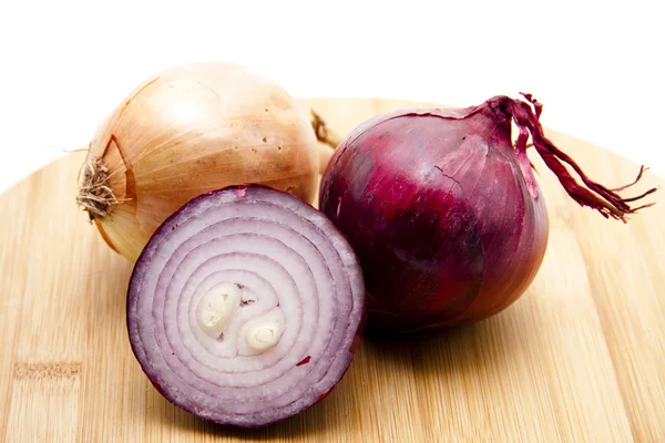 Red onions on wooden plate — Stock Photo, Image