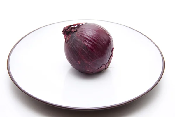 Raw red onion on plate — Stock Photo, Image