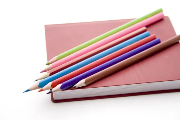 Цветные карандаши на книге — стоковое фото