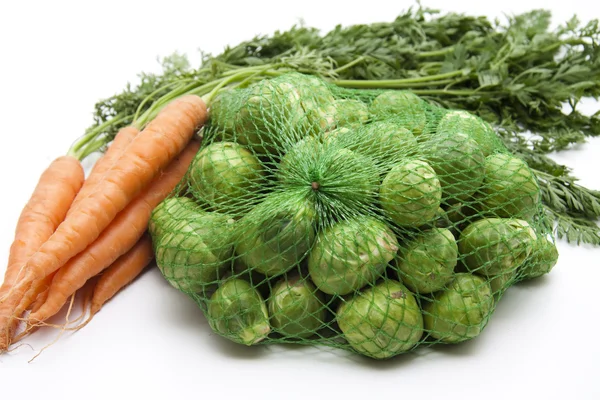 Brussels sprouts in the net and carrots — Stock Photo, Image