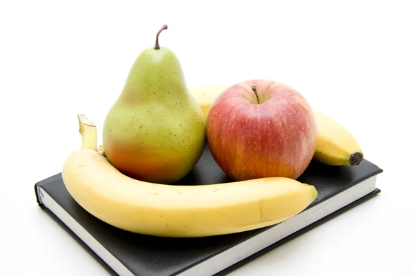 Яблоко и груша с бананом на книге — стоковое фото