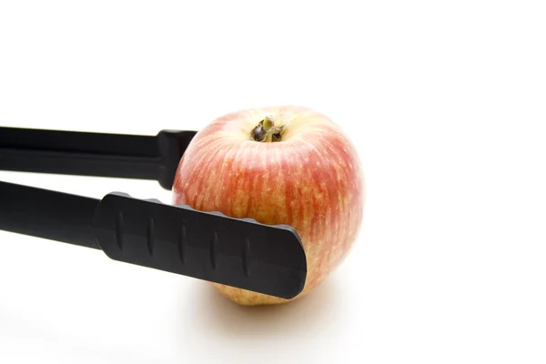 Apple with grill tongs — Stock Photo, Image