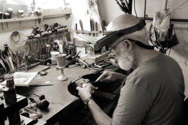 A very old jewelery shop and a jeweler in work clipart