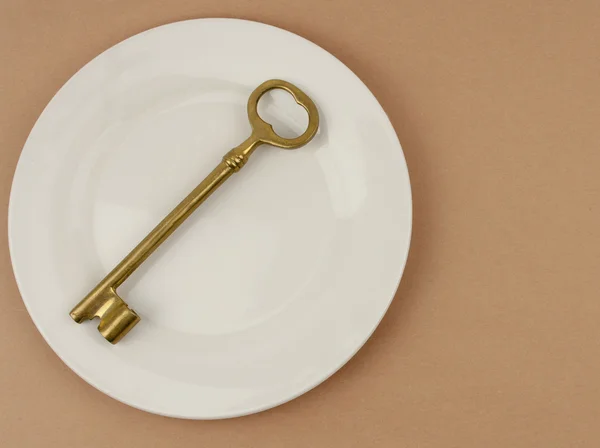 Llave dorada en una placa de cena — Foto de Stock