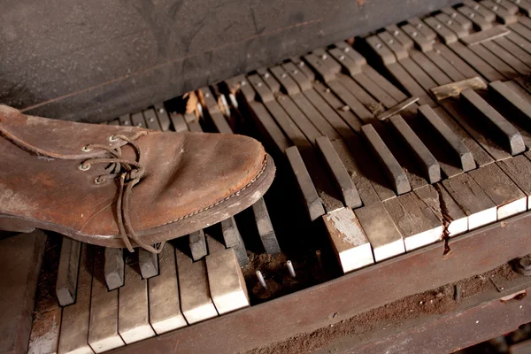 Oude vuile piano met oude lederen schoen — Stockfoto