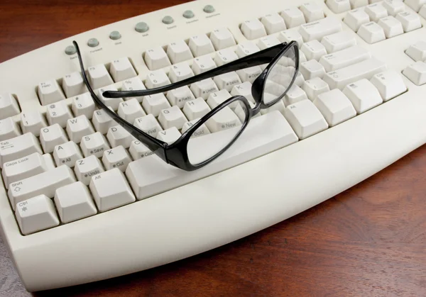 Leesbrillen op een witte toetsenbord — Stockfoto