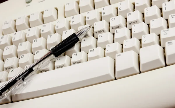 Перо на белой клавиатуре — стоковое фото