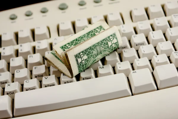 Dobrado um dólar contas em um teclado branco — Fotografia de Stock