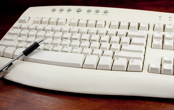 Długopis wskazujące na białym klawiatury — Zdjęcie stockowe