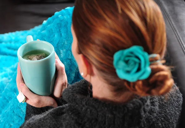 Mulher no sofá com cobertor e xícara de chá — Fotografia de Stock