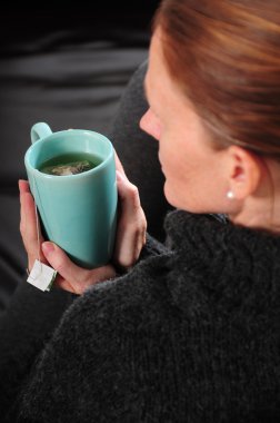 Sitting on couch with warm cup of tea clipart