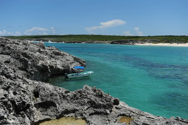 Tropikal bir ortamda kayalık ada yanındaki küçük tekne — Stok fotoğraf