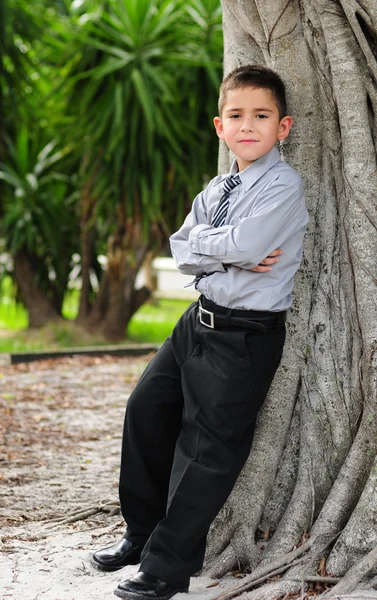 Allvarlig ung pojke lutade mot träd — Stockfoto