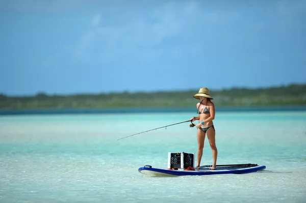 Mulher de biquíni pesca e paddle boarding — Fotografia de Stock