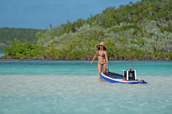 Donna tirando paddle board in mare — Foto Stock