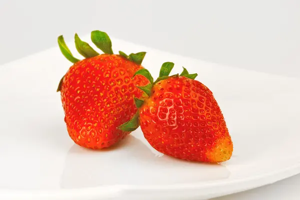 Две ягоды клубники на белой тарелке — стоковое фото