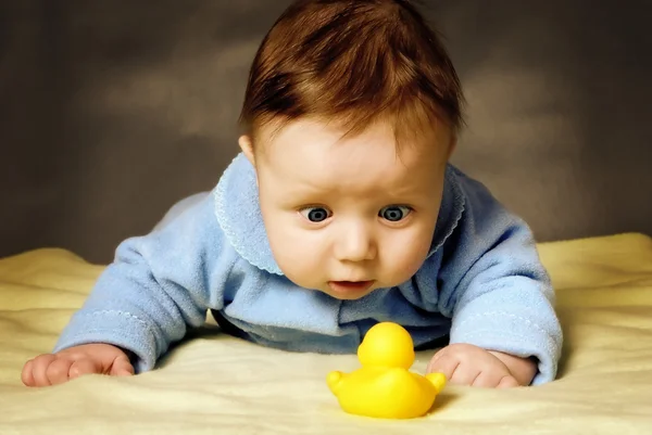 Dítě s překvapením považuje hračka kachna. — Stock fotografie