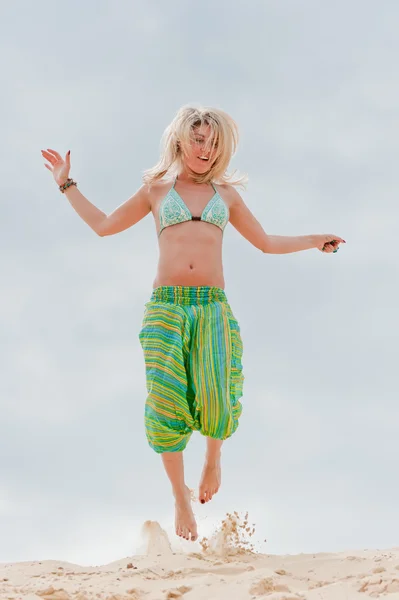 Jong meisje springen in het zand — Stockfoto