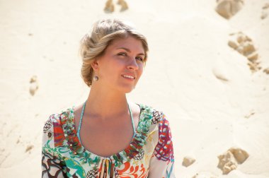 Portrait of a blonde in a sarafan on the background the sand dune