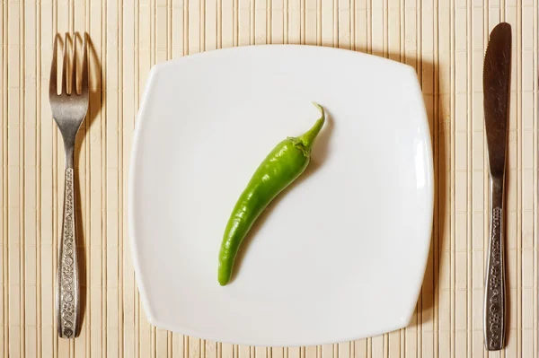Φρέσκια πράσινη πιπεριά, σε ένα λευκό τετράγωνο πιάτο. — Φωτογραφία Αρχείου