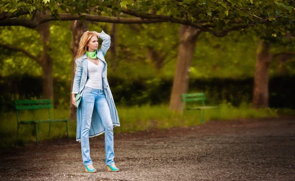 Приваблива молода жінка в джинсах, що йдуть в парку — стокове фото