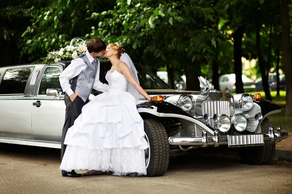 Brudgummen och bruden om retro limousine — Stockfoto