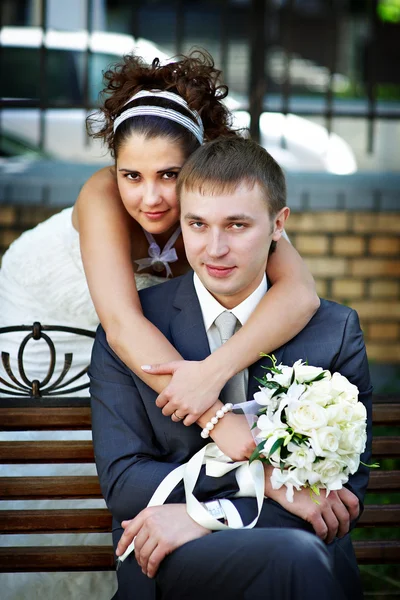 Happy bride and groom on park bench — Stock Photo, Image
