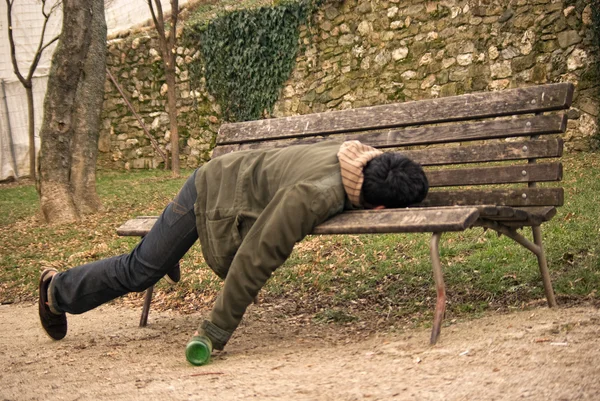 Drunk beggar sleeping on a bench with a bottle in hand — Stock Photo ...