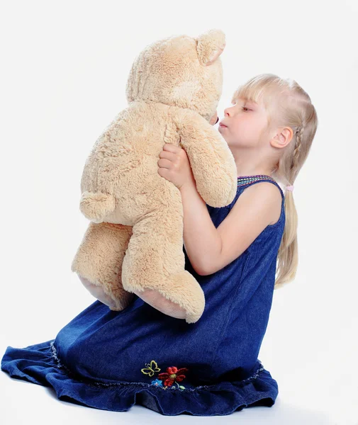 The lovely girl kisses the bear — Stock Photo, Image