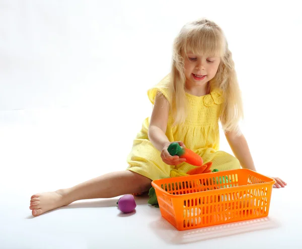 A menina coloca brinquedos no recipiente — Fotografia de Stock