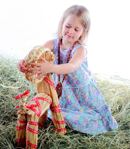 La chica juega en el heno juega con una cabra golpeada —  Fotos de Stock