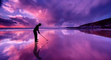 gün batımında sahilde topa vuruyor golfçü silüeti