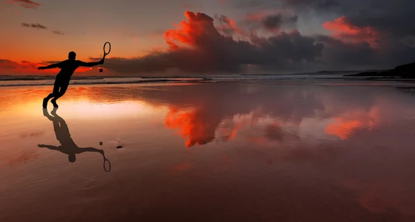 Sylwetka tenisista uderzenie balll na plaży o zachodzie słońca — Zdjęcie stockowe