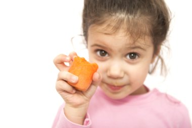 Little happiest girl holding a piece of carrot isolated on white clipart