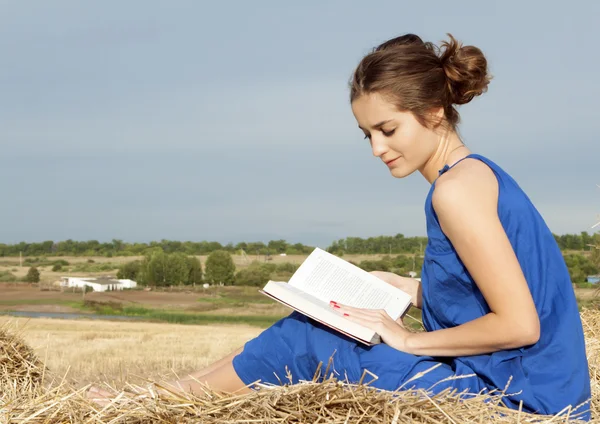 Mujer joven leyendo libro al aire libre sobre el heno — Foto de Stock