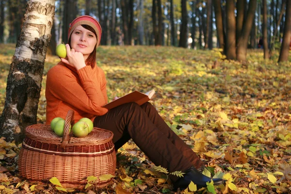 Young woman reading book in fall park — Stock Photo, Image
