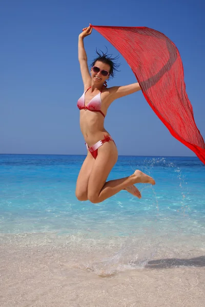 Sexy Frau springt am Strand mit bunten Tüchern — Stockfoto
