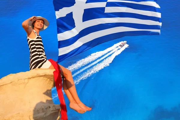 ギリシャの国旗と紺碧の海の上の岩の上にセクシーな女性 — ストック写真