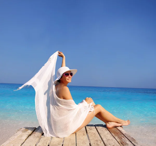 Сексуальная женщина в белом платье расслабляется против лазурного моря — стоковое фото