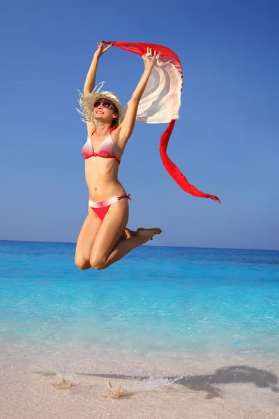 Счастливая девочка прыгает на пляже с шарфами — стоковое фото